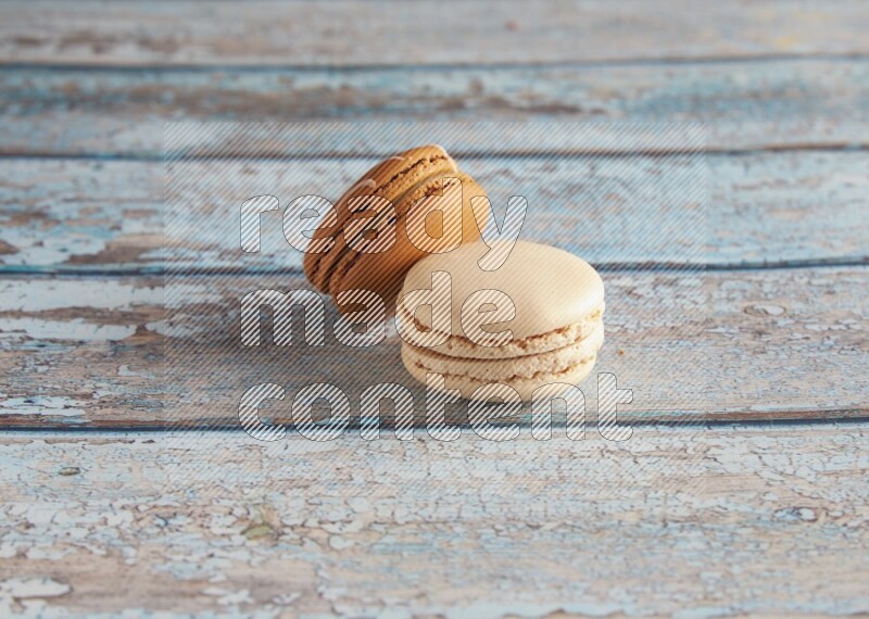 45º Shot of of two assorted Brown Irish Cream, and White Caramel fleur de sel macarons on light blue background