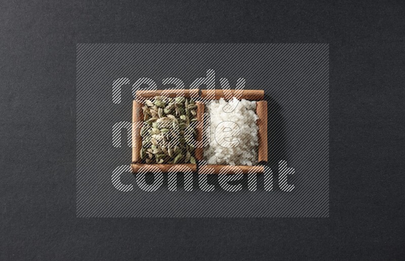 2 squares of cinnamon sticks full of white salt and cardamom on black flooring