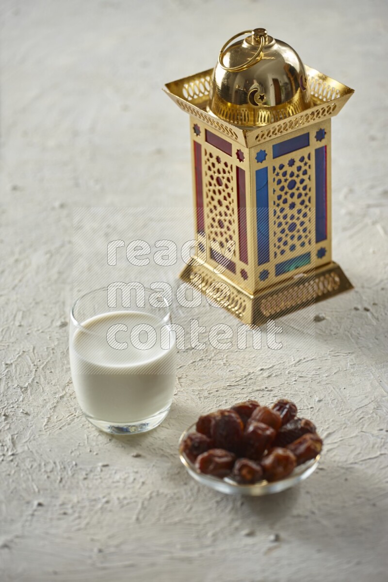 A golden lantern with different drinks, dates, nuts, prayer beads and quran on textured white background
