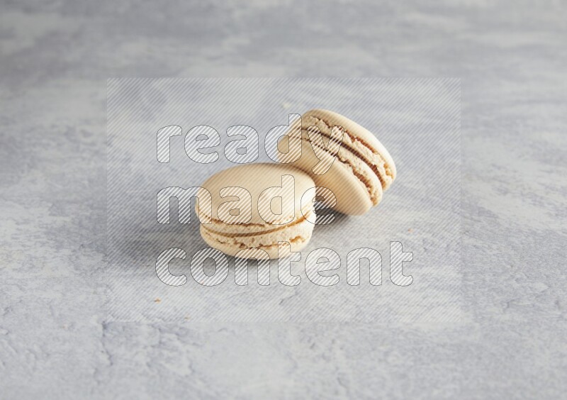 45º Shot of two white marbleCaramel fleur de sel macarons  on white  marble background