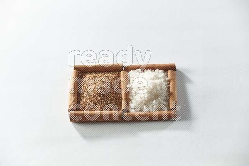 مربعان من أعواد القرفة ممتلئان بحبوب الخردل والملح الأبيض علي خلفية بيضاء