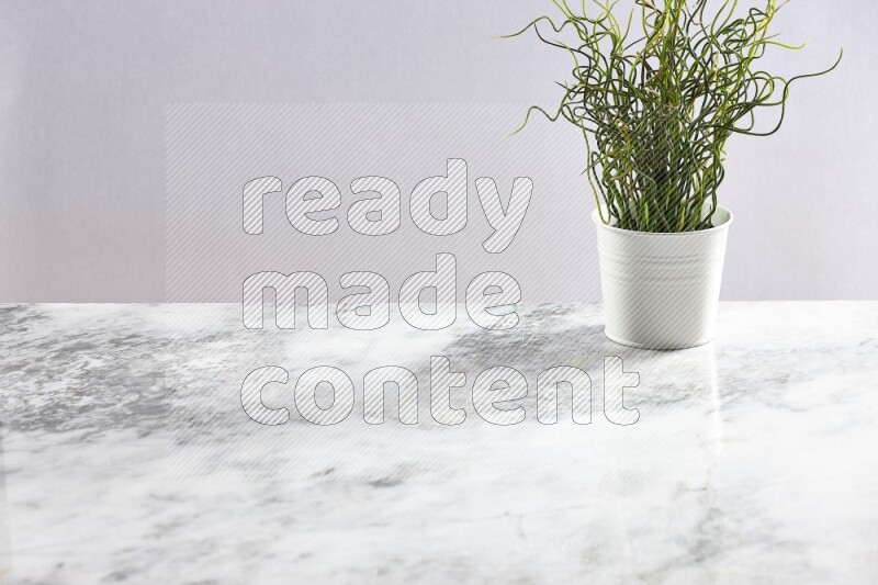 Green artificial plant in white pot on light grey marble background