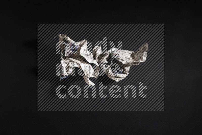 Crumpled newspaper sheet on black background