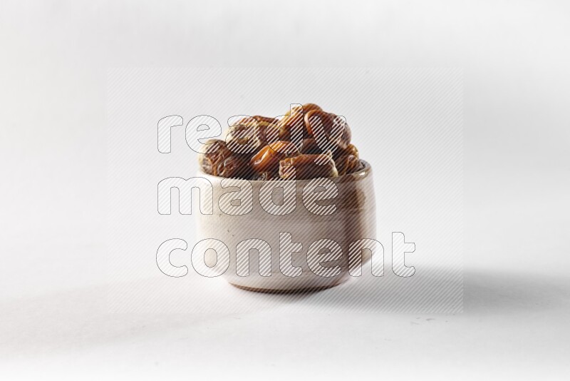 Dates in a beige pottery bowl on white background