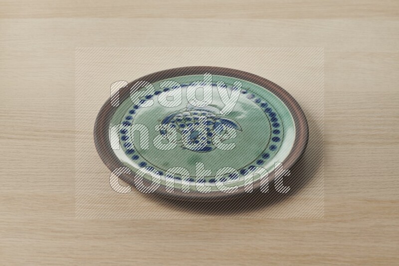 صحن فخاري مزخرف على خلفية خشبية فاتحة