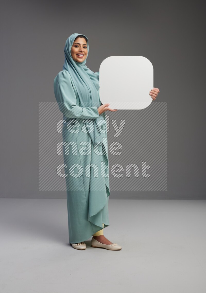 Saudi Woman wearing Abaya standing holding social media sign on Gray background