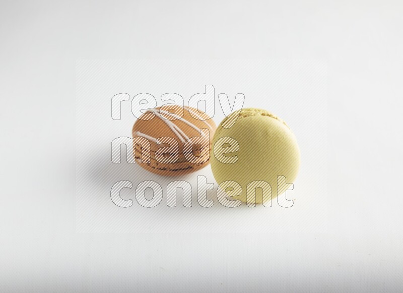 45º Shot of of two assorted Brown Irish Cream, and Yellow Lime macarons on white background