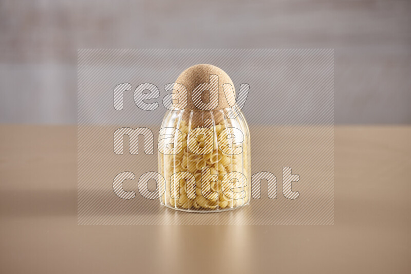 Raw pasta in glass jars on beige background