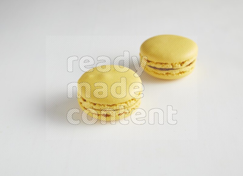 45º Shot of two Yellow Lemon macarons on white background