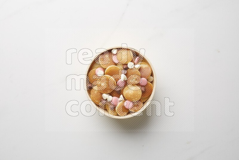 Top-view shot of mixed chocolate chips cereal pancakes in a round bowl on white background