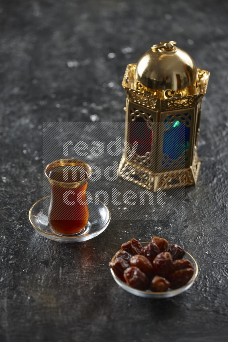 A golden lantern with different drinks, dates, nuts, prayer beads and quran on textured black background