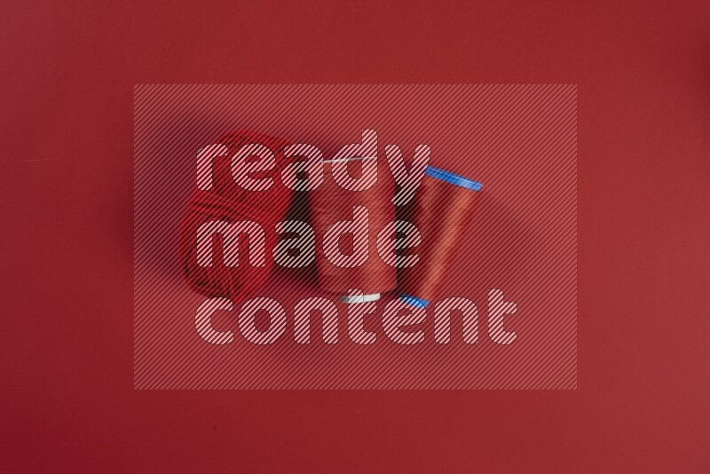 مجموعة من أدوات الخياطة والتفصيل حمراء اللون على خلفية حمراء