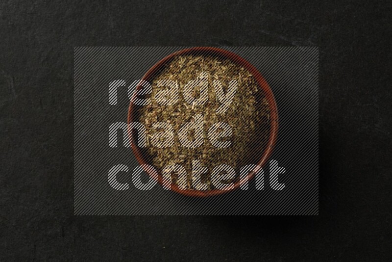 wooden round sauce bowl filled with herbs on grey textured countertop