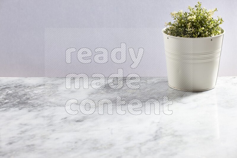 Artificial plant in white pot on grey marble background