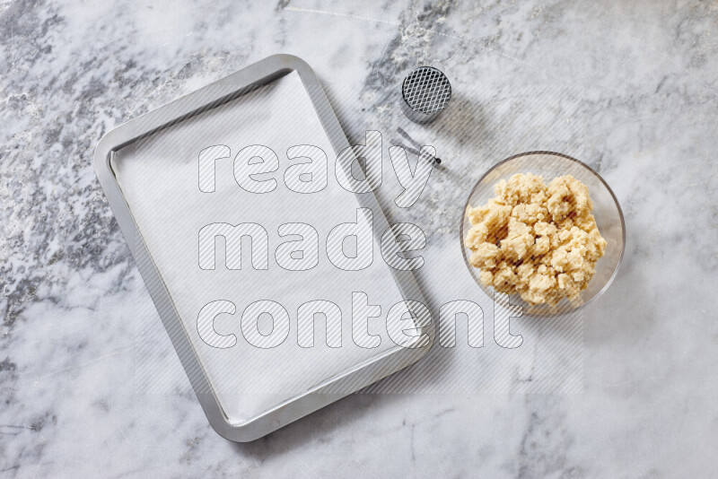 كحك خطوة بخطوة بمكوناته سمن، سكر، دقيق، سمسم، خميرة، ماء ونكهة الكحك على خلفية رخام رمادي