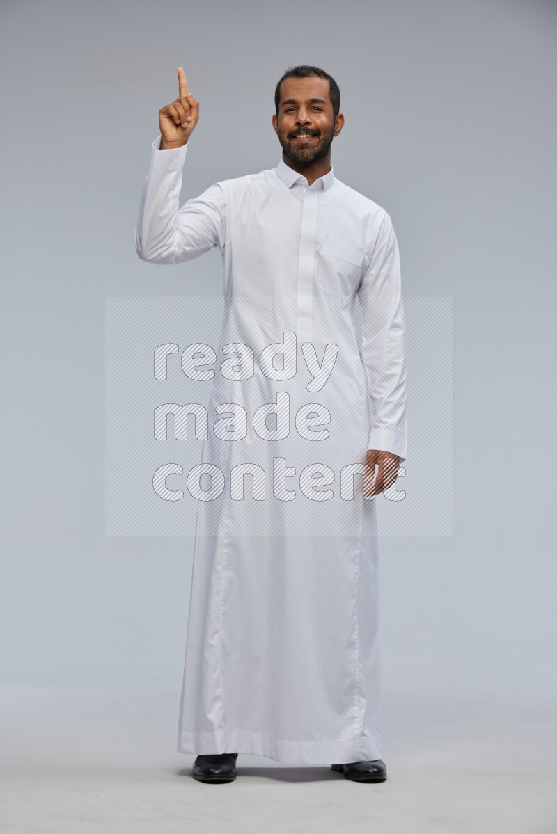 Saudi man Wearing Thob standing interacting with the camera on Gray background