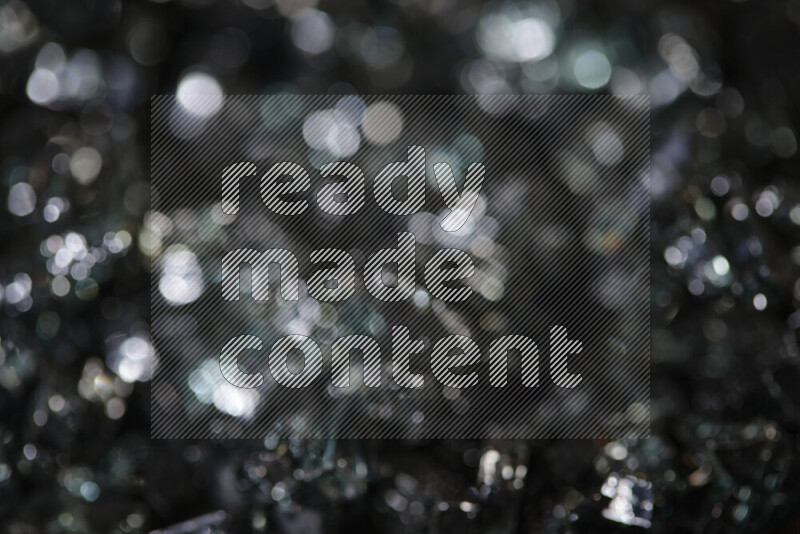 Transparent black fragments of glass scattered on a black background