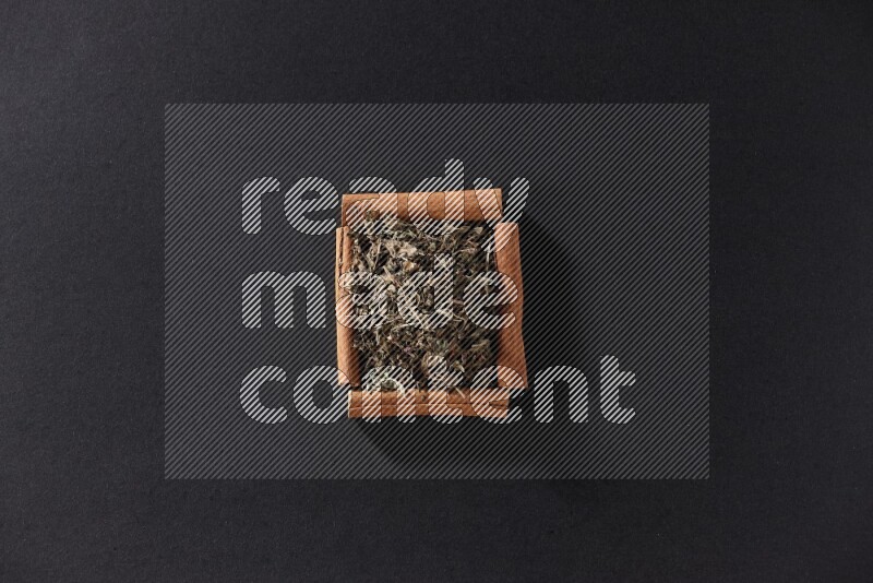 A single square of cinnamon sticks full of dried basil on black flooring