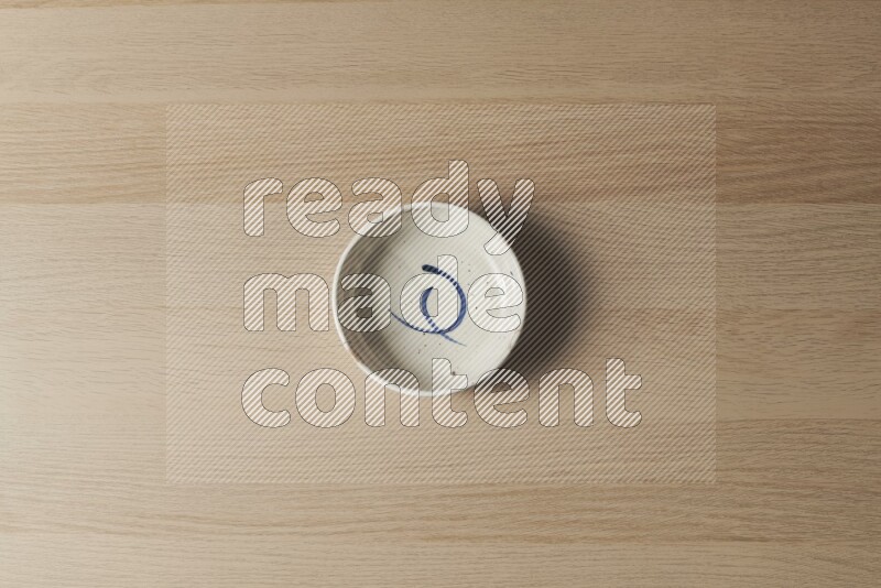 وعاء فخاري متعدد الألوان على خلفية خشبية فاتحة