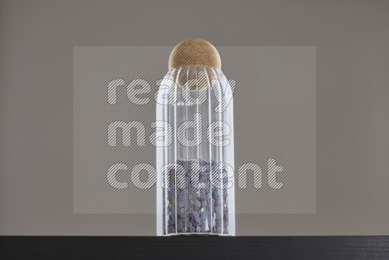 Sequins in a glass jar on black background