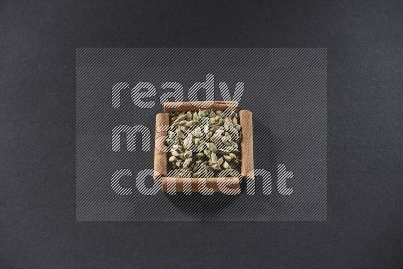 A single square of cinnamon sticks full of Cardamom on black flooring