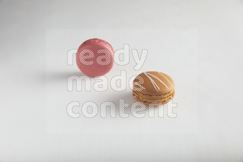 45º Shot of of two assorted Brown Irish Cream, and Pink Raspberry macarons on white background