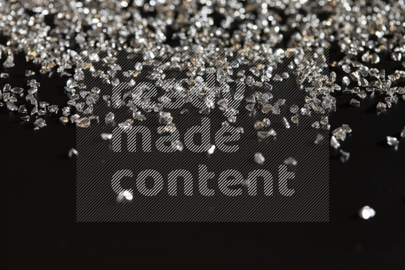 Silver shimmering fragments of glass scattered on a black background