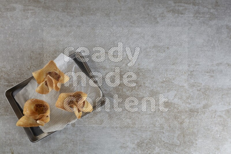 wonton cups on parchment paper in stainless tray on grey textured counter top