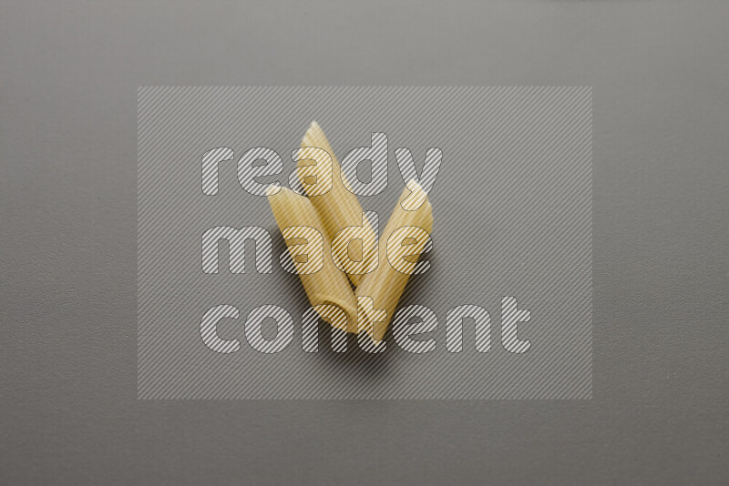 Mini penne pasta on grey background