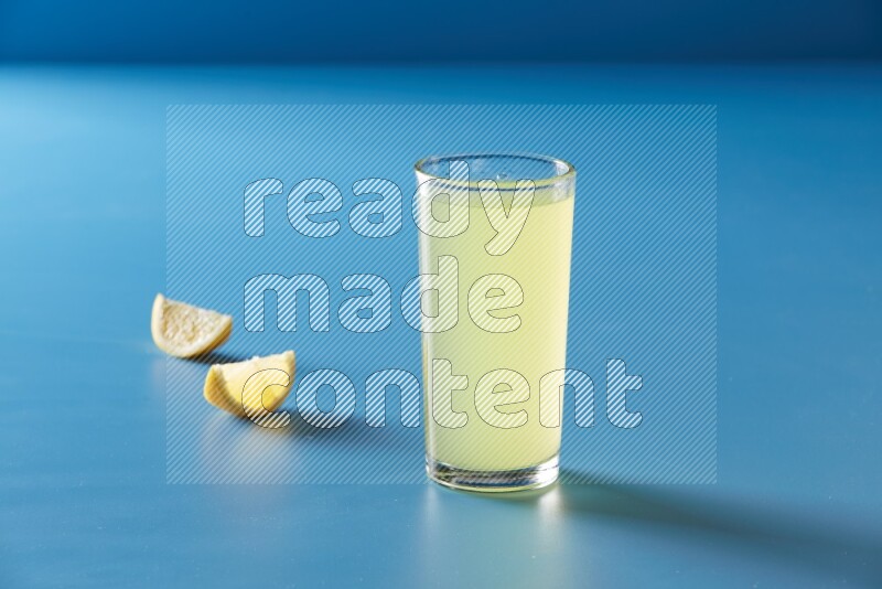 glass of lemon juice on blue background