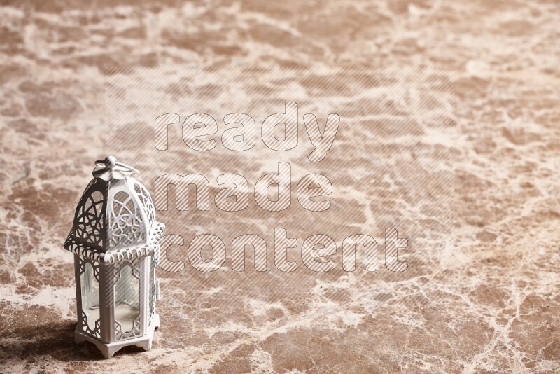 A candle lantern on beige marble background