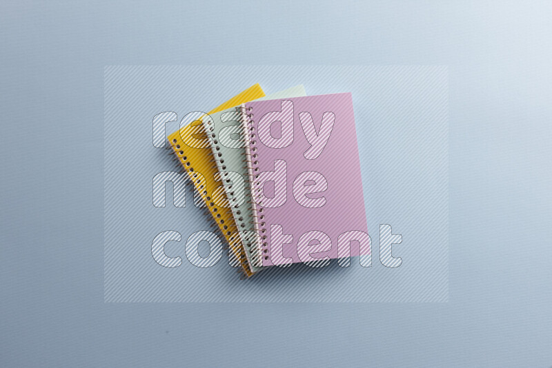 Multicolored notebooks with different school supplies on blue background