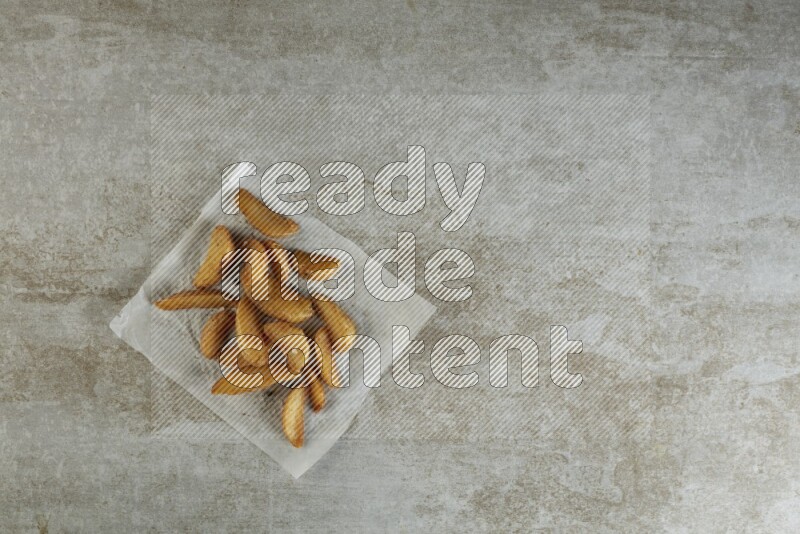 wedges potato on parchment paper on grey textured counter top