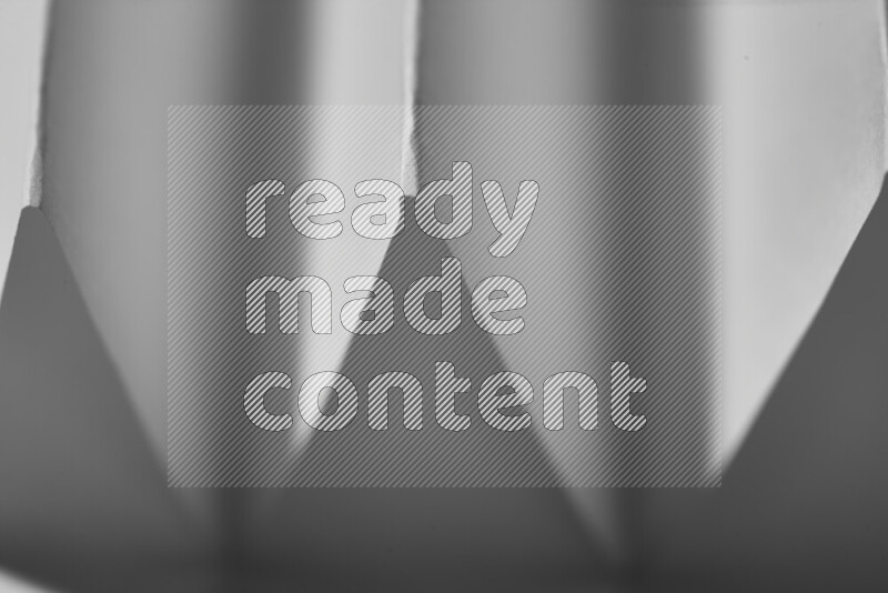 A close-up abstract image showing sharp geometric paper folds in grey gradients