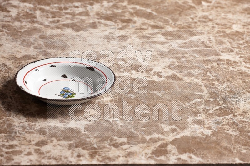 صحن معدني عتيق على خلفية رخام بيج