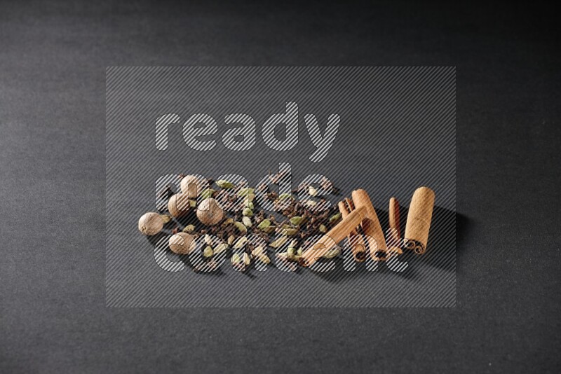 الهيل والقرنفل وجوزة الطيب وأعواد القرفة على خلفية سوداء