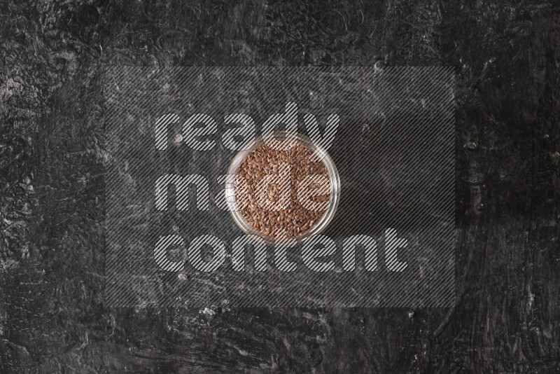 وعاء زجاجي ممتلئ بحبوب بذر الكتان علي خلفية سوداء