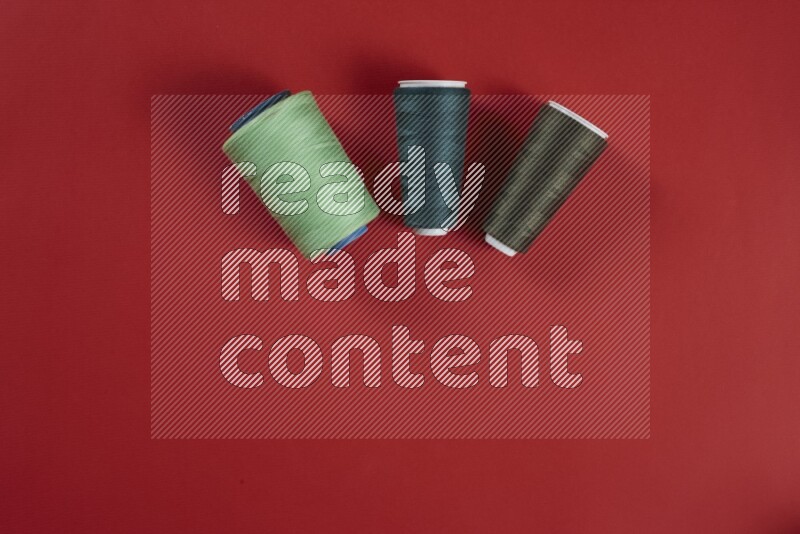 مجموعة من أدوات الخياطة والتفصيل خضراء وحمراء اللون على خلفية حمراء