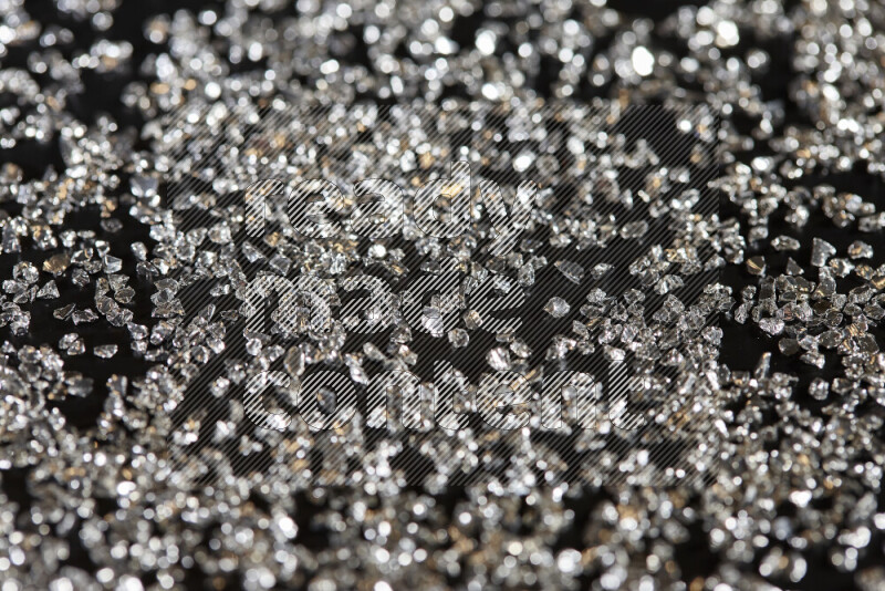 Silver shimmering fragments of glass scattered on a black background