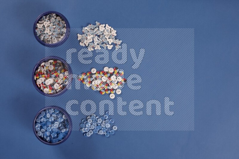 أوعية فخارية متعددة الألوان مليئة بالأزرار الملونة على خلفية زرقاء