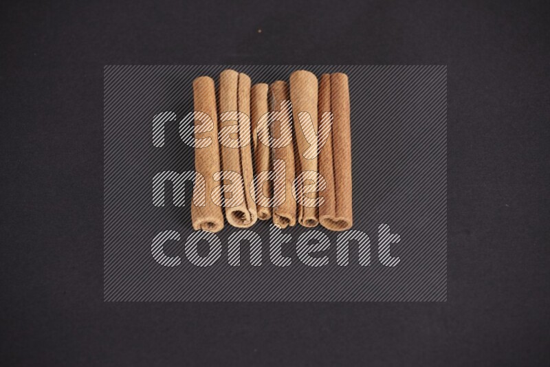 Cinnamon sticks stacked on black flooring