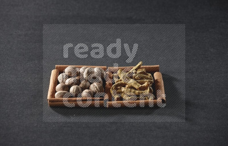 2 squares of cinnamon sticks full of nutmeg and turmeric fingers on black flooring