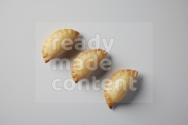 Three fried sambosa from a top angle on a white background