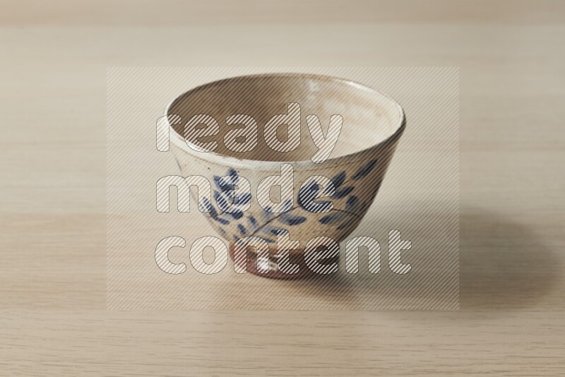 A decorative pottery bowl on light wooden background