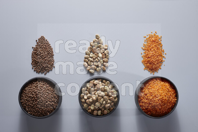 Legumes in pottery bowls on light grey background