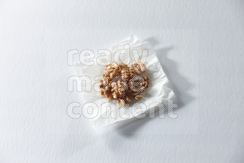 Peeled walnuts on a crumpled piece of paper on a white background in different angles
