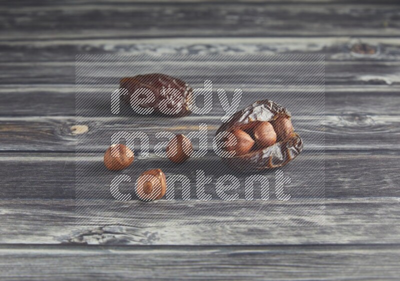 two hazelnut stuffed madjoul dates on a wooden grey background