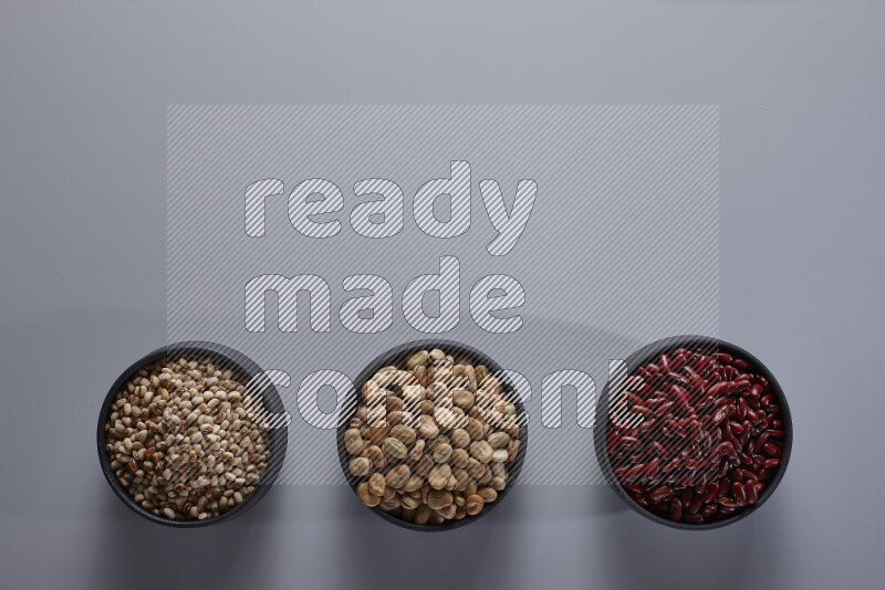 Legumes in pottery bowls on light grey background