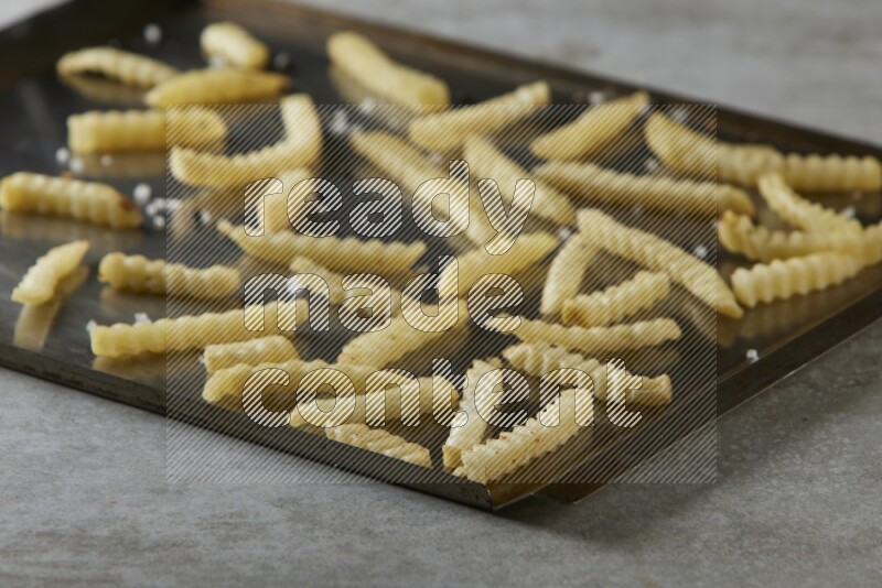 crinkle fries in a black stainless steel rectangle tray on grey textured counter top