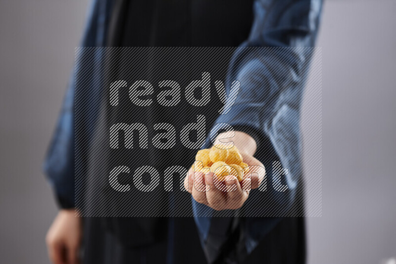 Woman in abaya holding different kinds of snacks in different positions